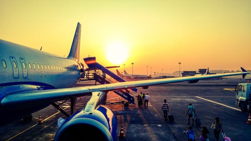 Passengers boarding a plane at sunset — group flight booking tips to save money