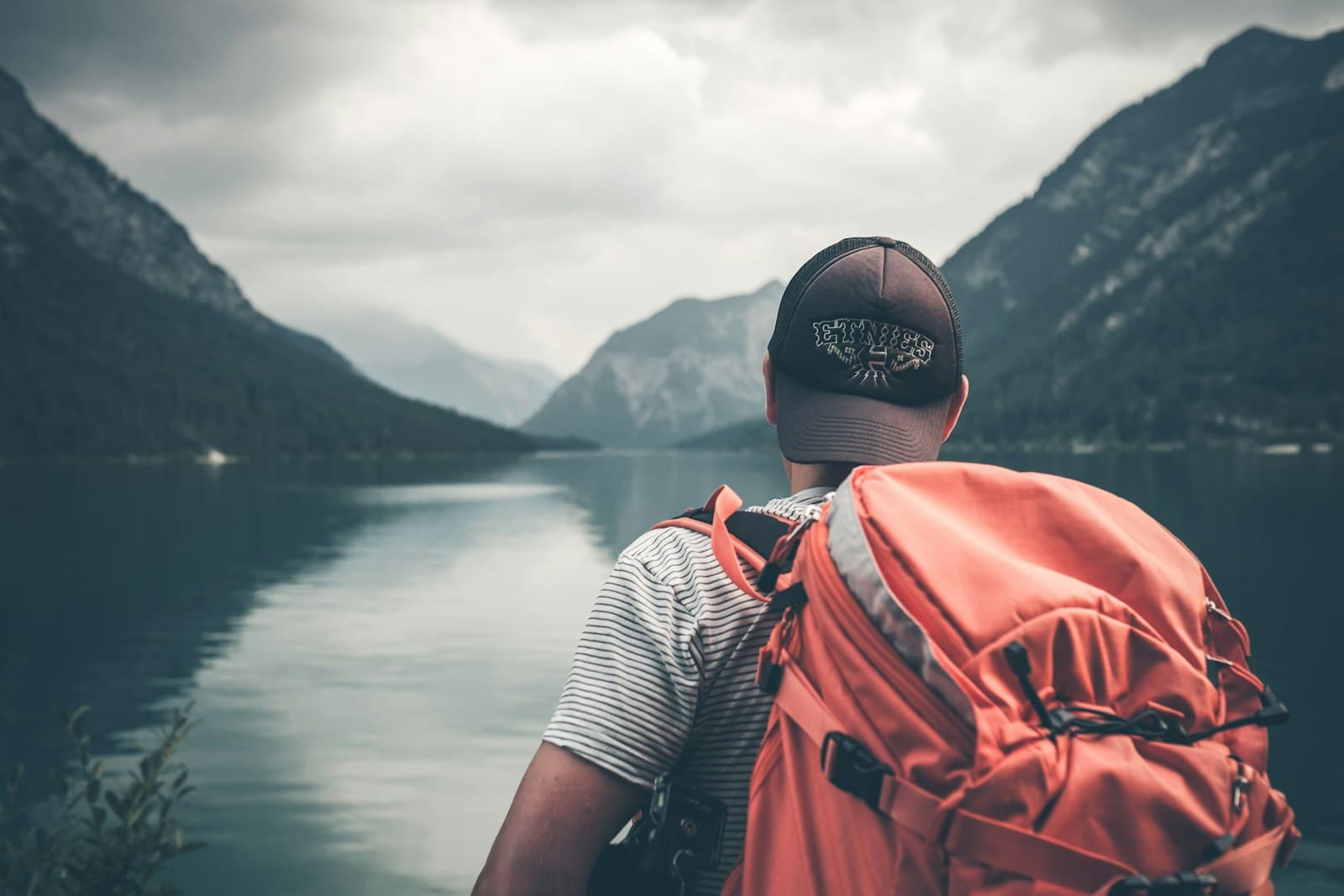 Backpacker looking out over a lake while travelling on a budget