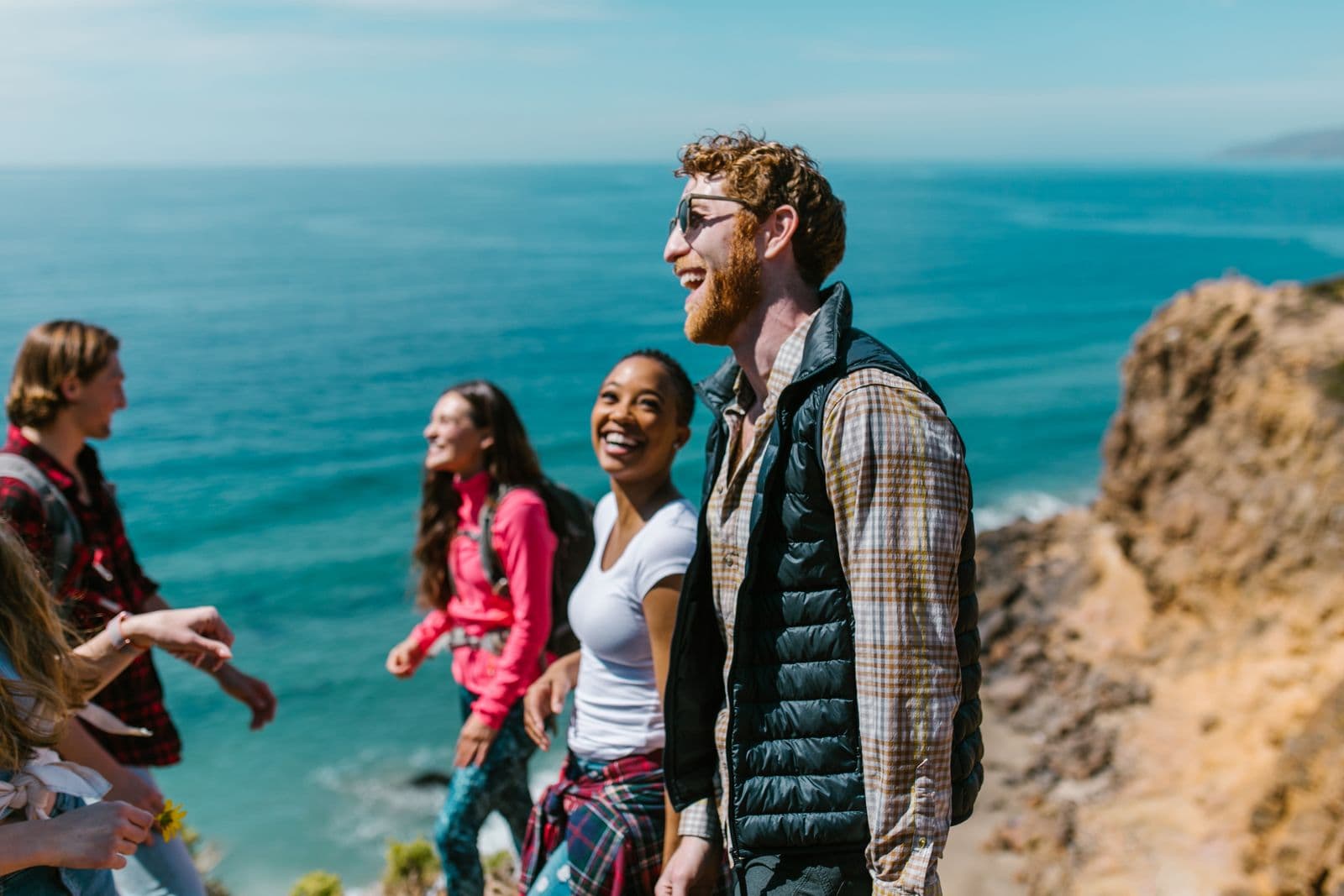 A group of friends laughing together on a coastal walk on a group trip