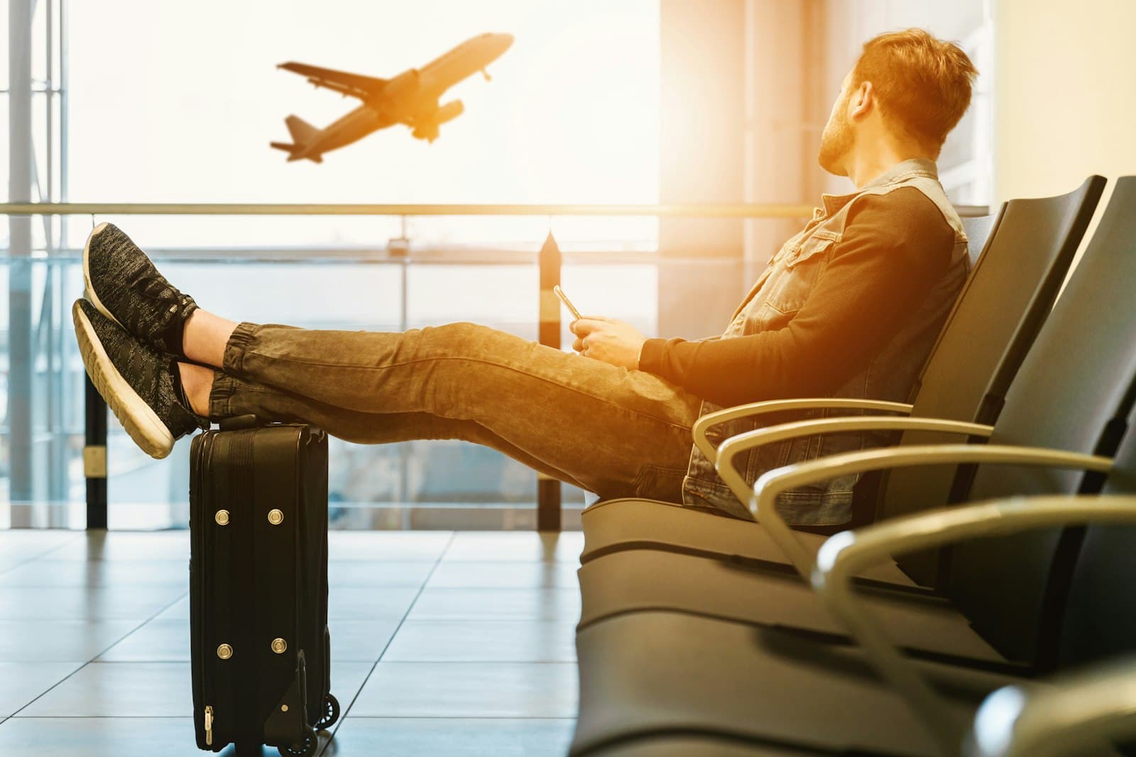 A traveller watching a plane take off from an airport departure lounge