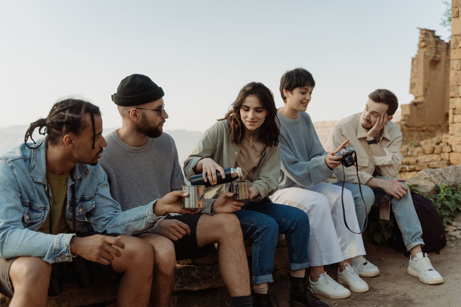 A group of friends sitting together outdoors, talking things over with a drink
